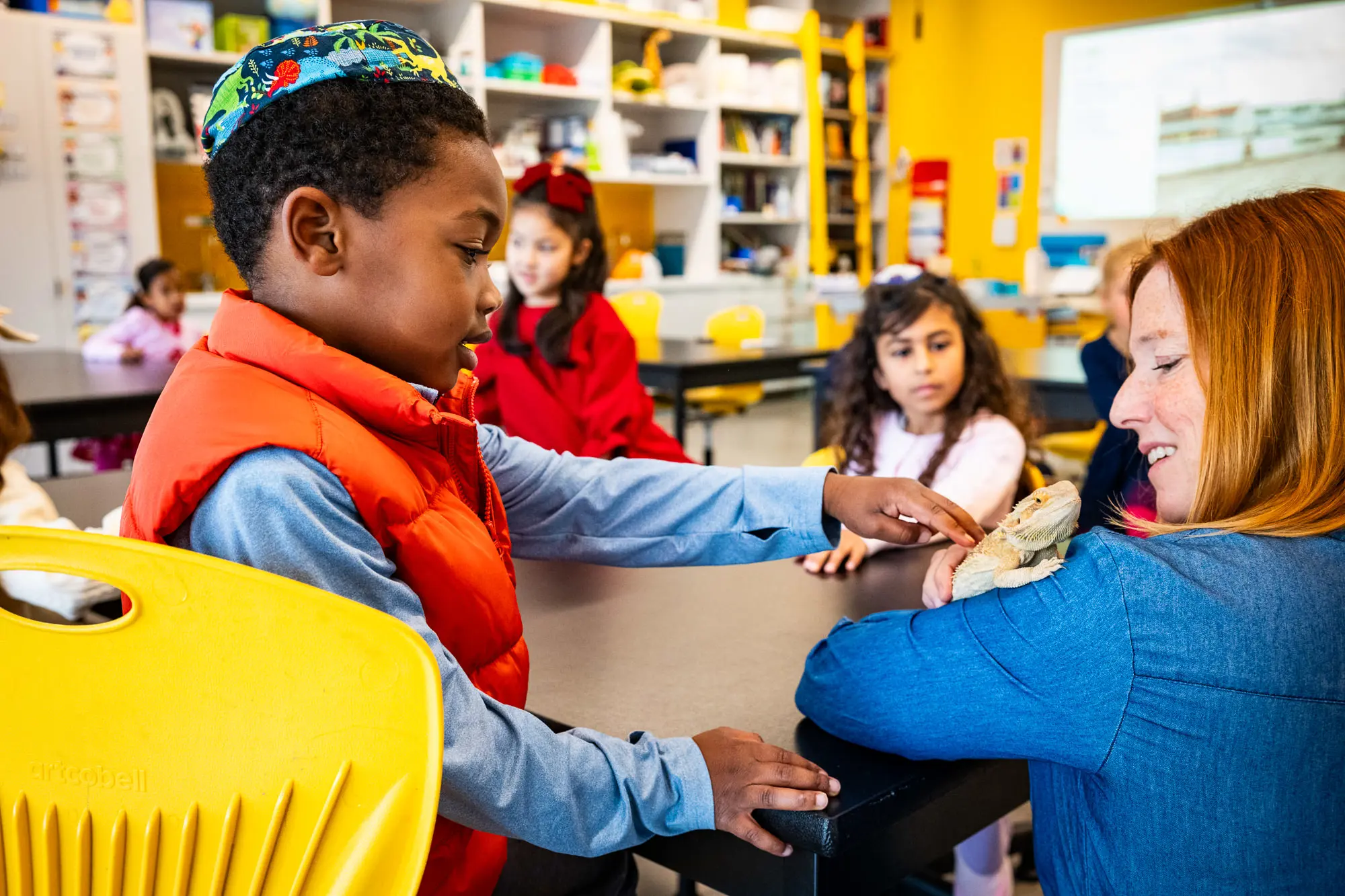 Student reaching out to touch reptile