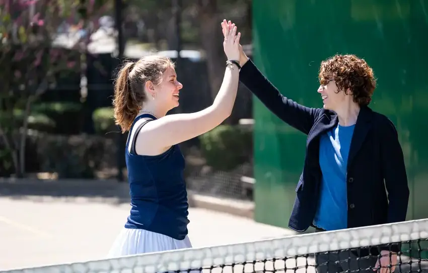 Student tennis player high-fiving coach