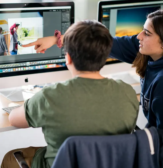 Upper school students pointing at computer screen