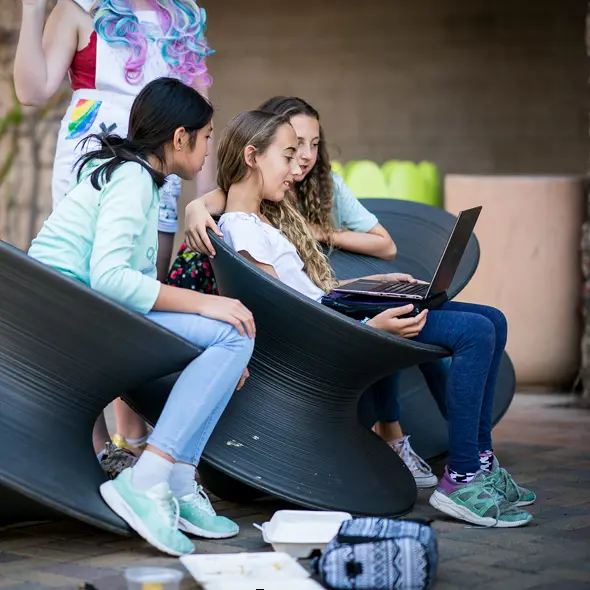Middle school students sitting on sofa, looking at laptop